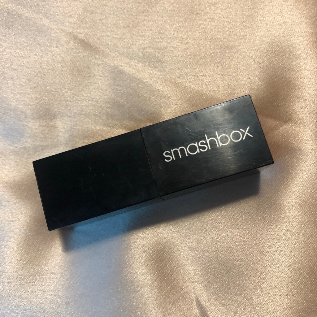 A photo of Smashbox Be Legendary Lipstick in shade Bing Matte which is a true blue red color. The black square lipstick component rests on a caramel silk sheet.